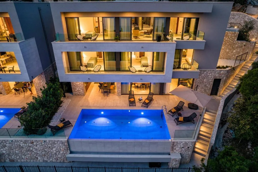 Aerial night view of Villa Helia with lit pool and terraces