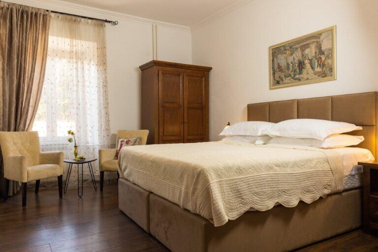 Schlafzimmer mit Kingsize-Bett und antiker Garderobe in der Villa Le Jardin