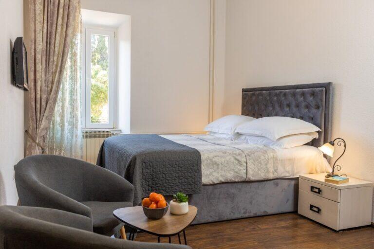 Schlafzimmer mit Kingsize-Bett und grauer Kopfteil im Villa Le Jardin