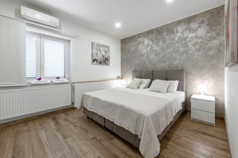 Schlafzimmer mit Queensize-Bett und grauer Zierwand an der Villa Mlini
