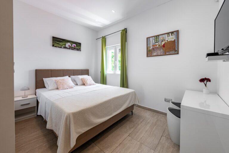 Schlafzimmer mit Queensize-Bett und grünen Vorhängen in der Villa Mlini