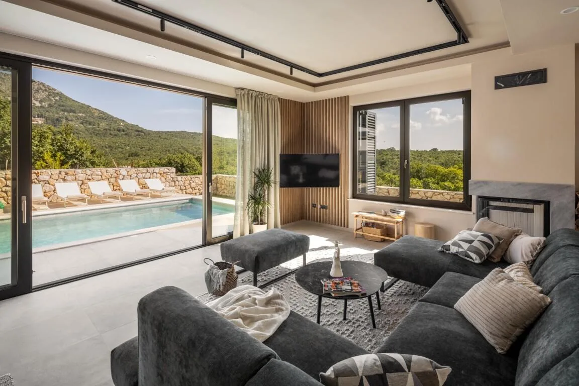 Living room with sofa and glass doors opening to the pool at Villa Petra