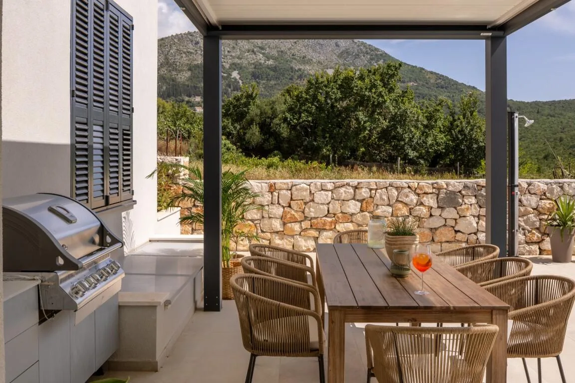 Outdoor dining table and barbecue under a pergola at Villa Petra