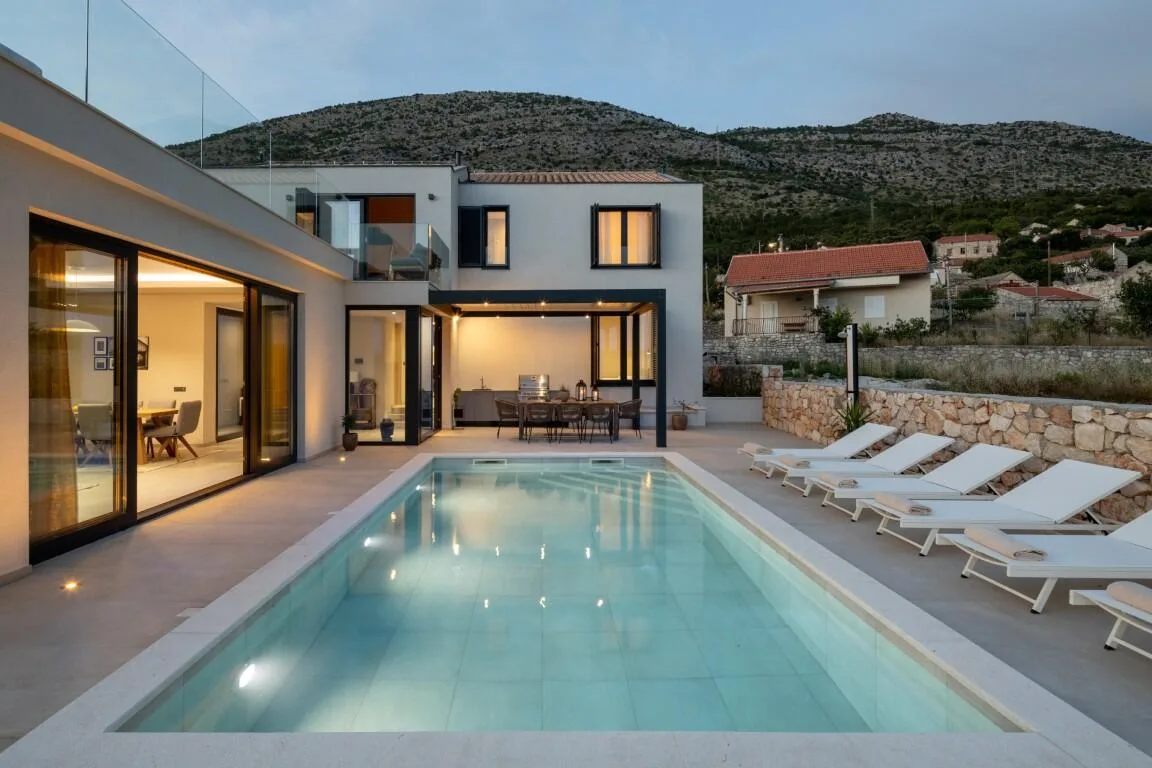 Heated pool and modern Villa Petra lit at dusk in the Majkovi countryside