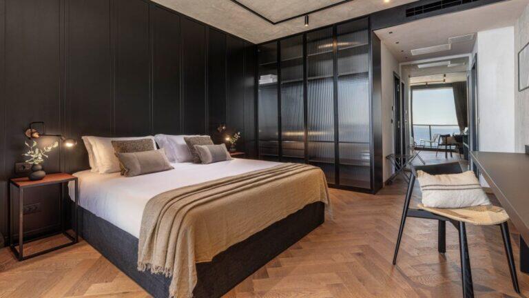 Schlafzimmer mit Kingsize-Bett und dunkler Garderobenwand in der Villa Atreeum