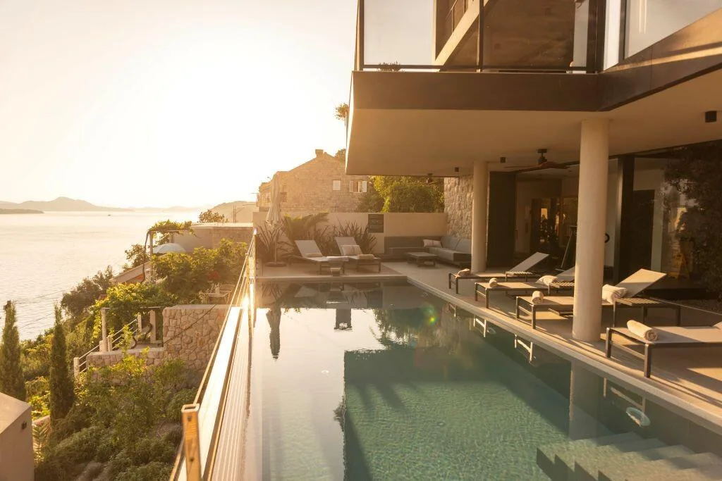 Infinity pool and loungers on the hillside above the sea at Villa Atreeum