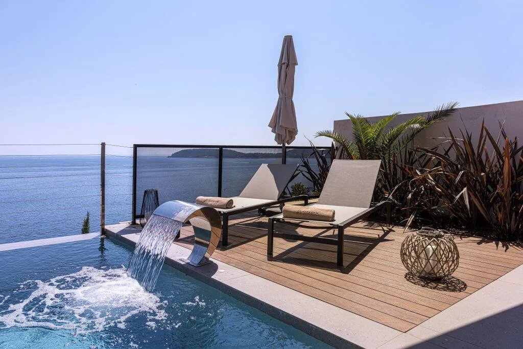 Pool waterfall feature and sun loungers with sea view at Villa Atreeum
