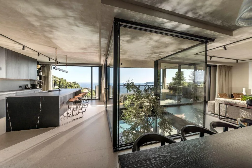 Glass atrium with a living tree at the heart of the kitchen and living area at Villa Atreeum