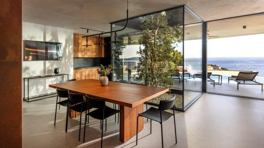 Dining table beside the tree atrium with sea views at Villa Atreeum