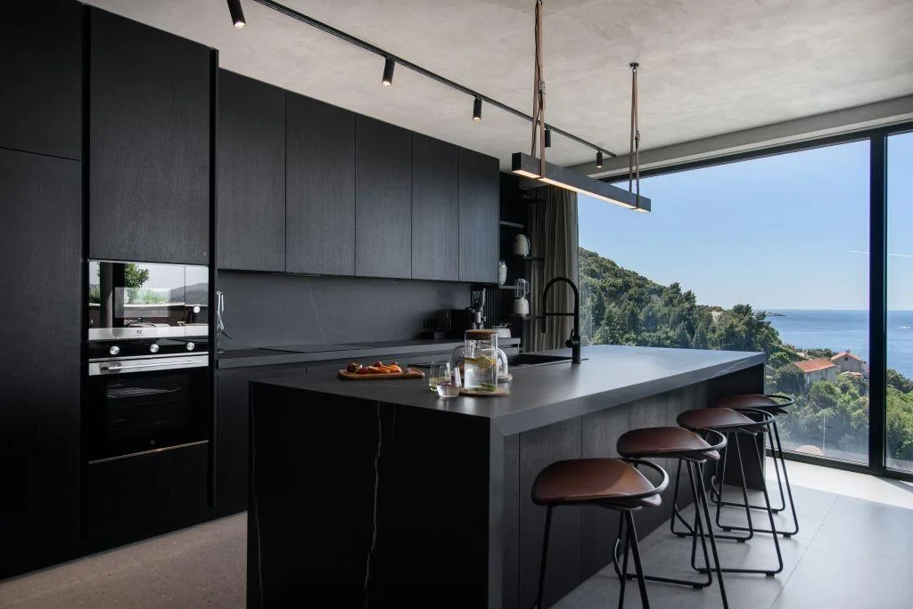 Black designer kitchen with island and bar stools at Villa Atreeum