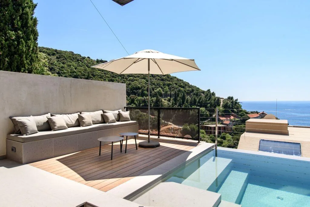 Outdoor lounge with parasol above the pool and sea at Villa Atreeum