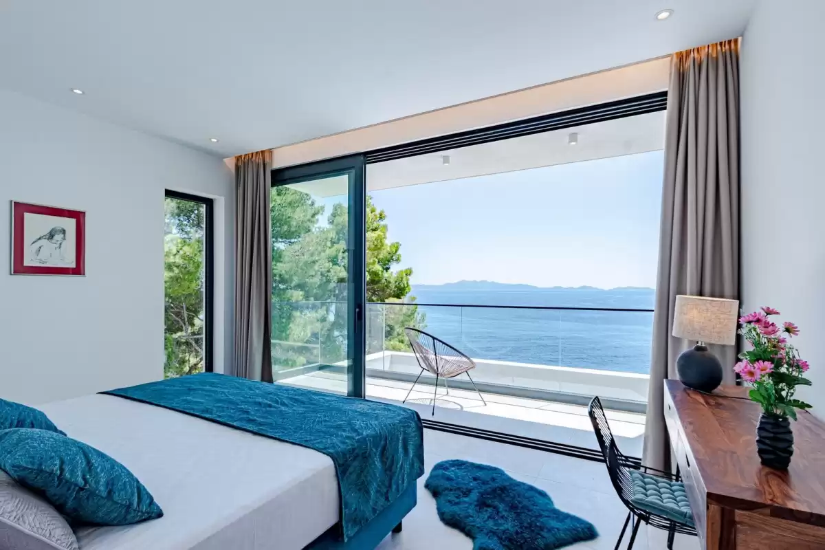 Bedroom with sea-view balcony and teal bedding at Villa Sansarea