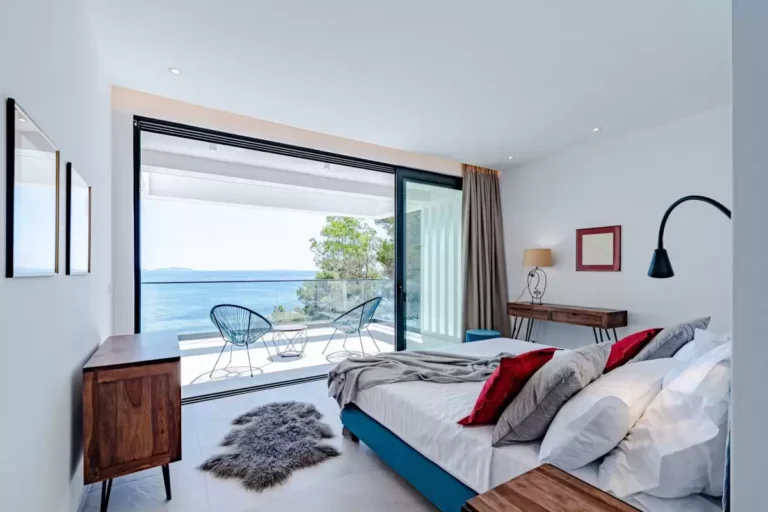 Bedroom with king-size bed and balcony overlooking the sea at Villa Sansarea