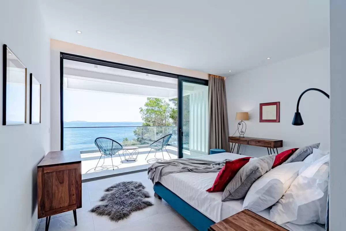 Bedroom with king-size bed and balcony overlooking the sea at Villa Sansarea
