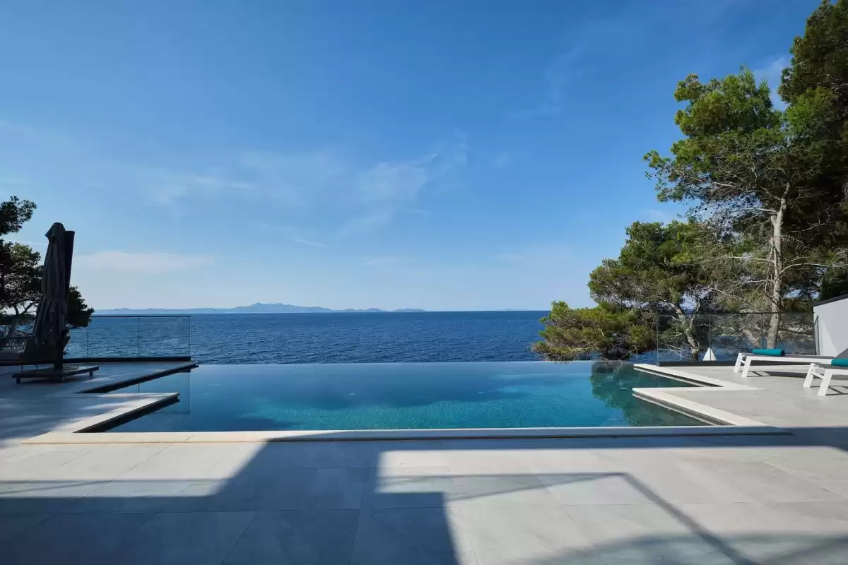Infinity pool edge merging with the open sea at Villa Sansarea