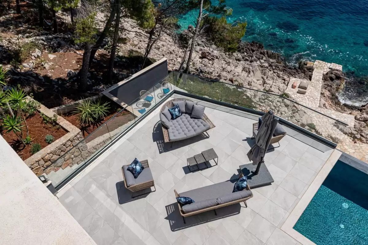 Aerial view of the lounge terrace and pool above the sea at Villa Sansarea
