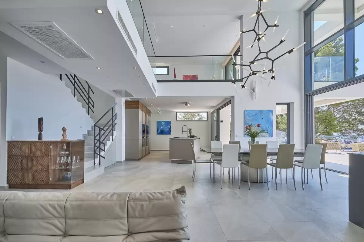 Double-height living and dining area with staircase at Villa Sansarea