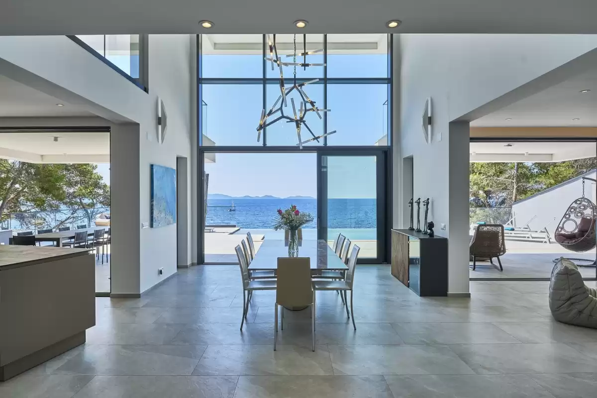 Dining table under a designer chandelier with sea view at Villa Sansarea