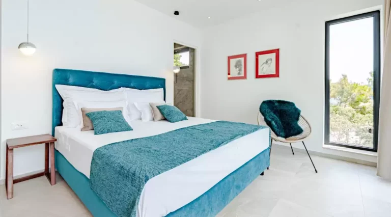 Bedroom with teal king-size bed and armchair at Villa Sansarea