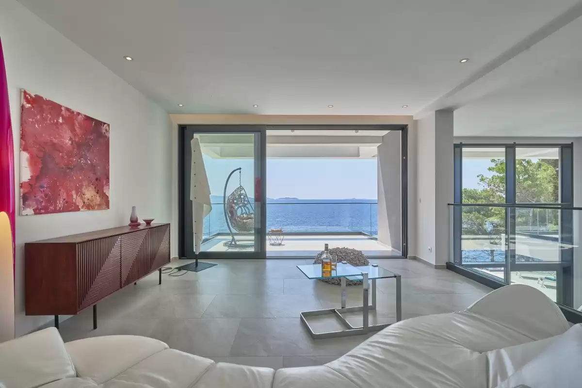 Lounge with white sofa and large windows facing the sea at Villa Sansarea
