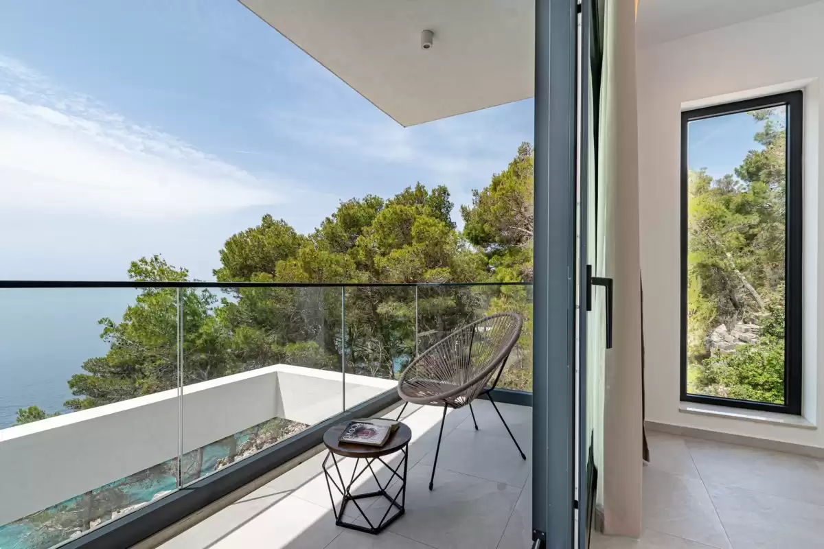Glass-railed balcony with pine trees and sea views at Villa Sansarea