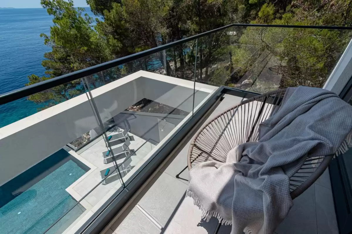 Balcony with hanging chair overlooking the pool and sea at Villa Sansarea