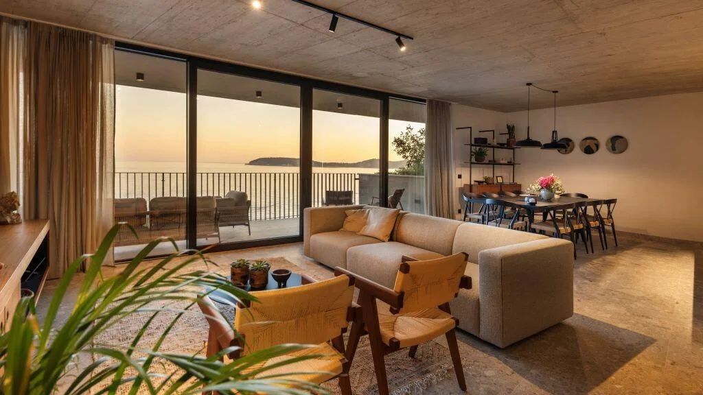 Salon ouvert avec des canapés et des fenêtres qui s’étendent du sol au plafond donnant sur la mer à Villa Eleven