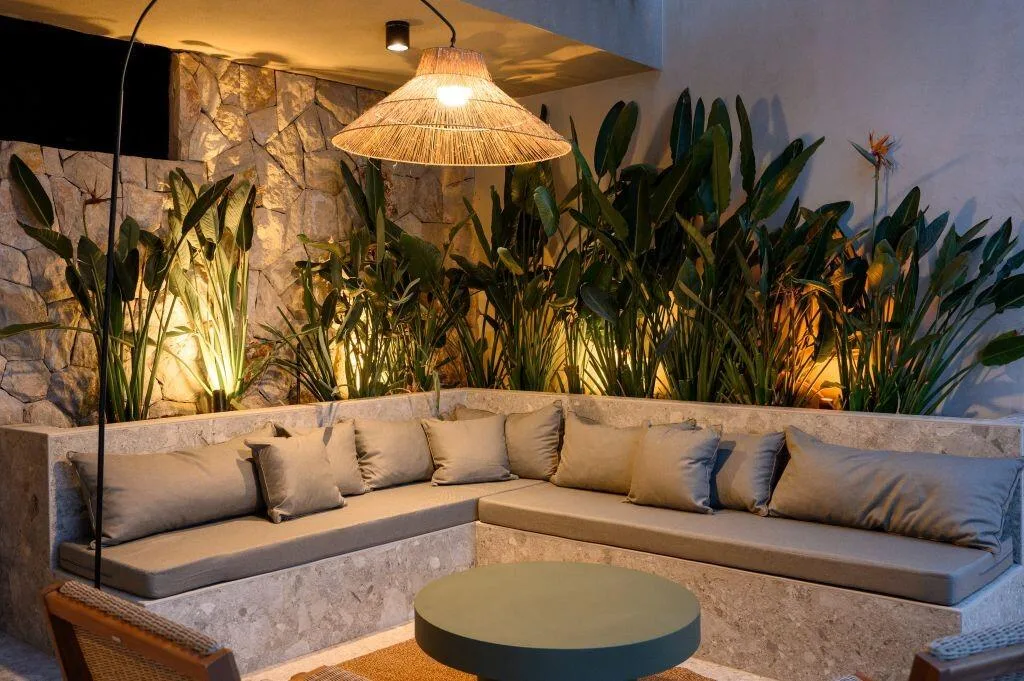 Salon de soirée avec canapé intégré, plantes et éclairage chaleureux à Villa Eleven