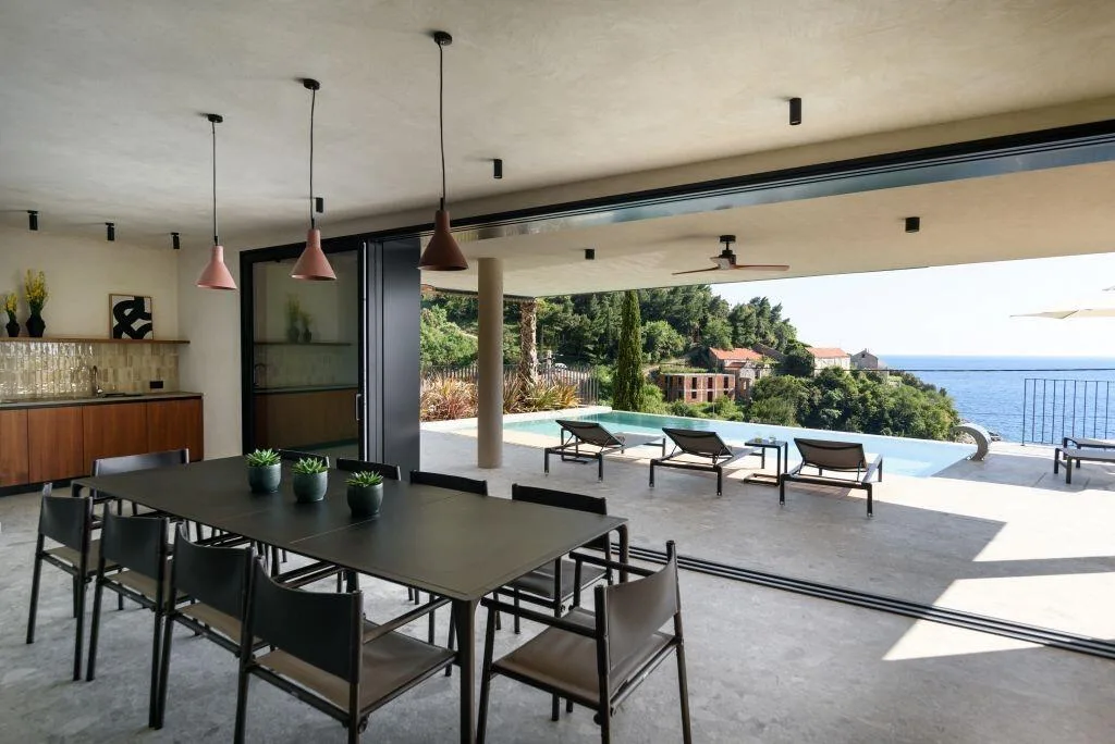 Table de salle à manger intérieure donnant sur la terrasse en bord de piscine avec vue sur la mer à Villa Eleven