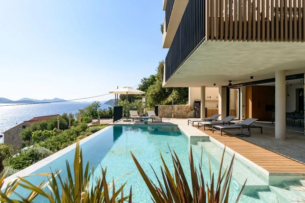 Piscine à débordement chauffée et chaises longues à Villa Eleven avec vue sur la mer sur la baie de Zaton
