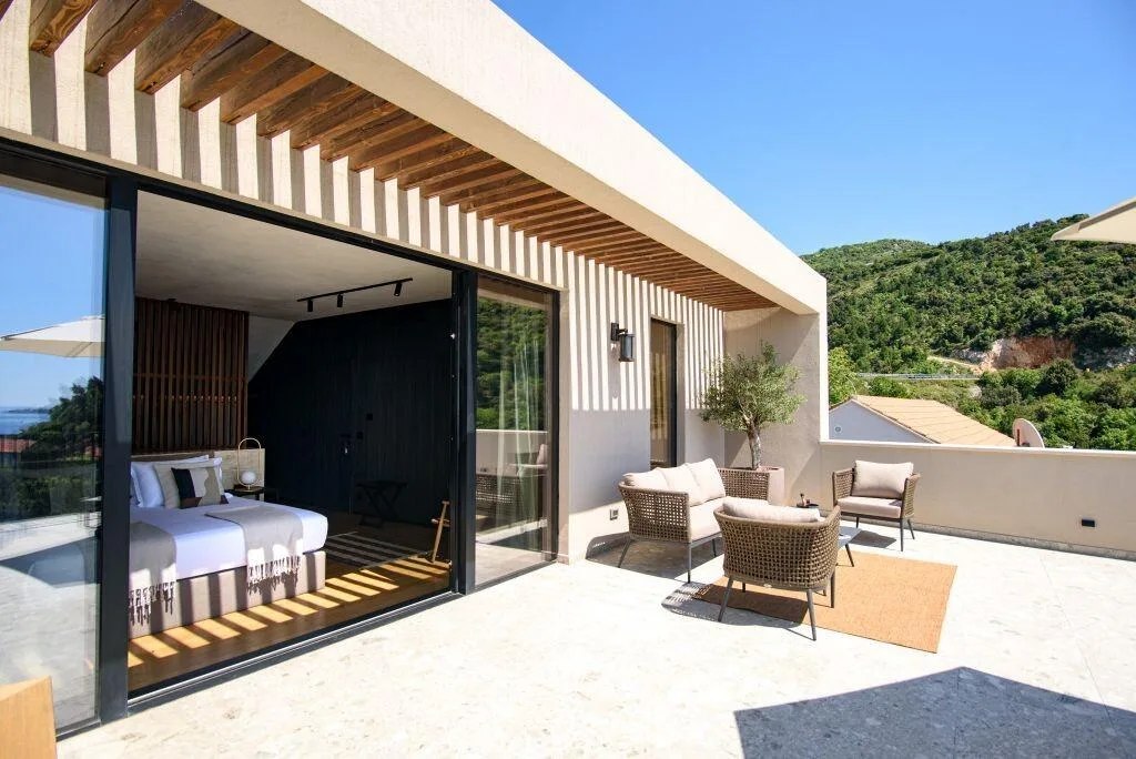 La chambre à coucher donne accès à une terrasse privée avec vue sur la mer, dotée de sièges en plein air à Villa Eleven