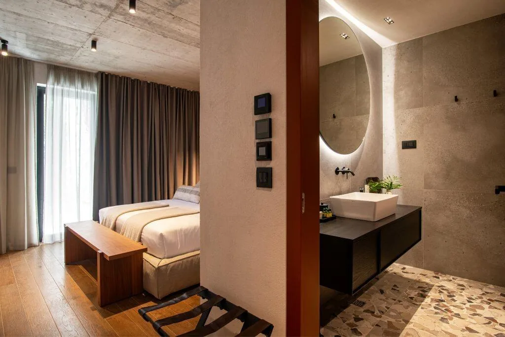 Chambre à coucher avec salle de bains privative et miroir rond éclairé à Villa Eleven