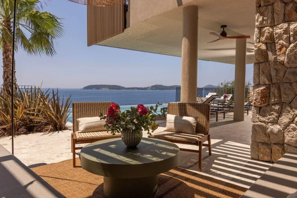 Salon extérieur avec des fauteuils et vue sur la mer sur la terrasse couverte de Villa Eleven