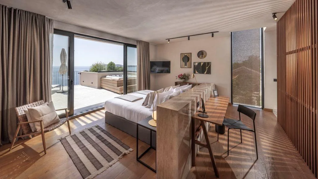 Chambre à coucher avec un lit king-size, un bureau et une terrasse donnant sur la mer à Villa Eleven, Zaton