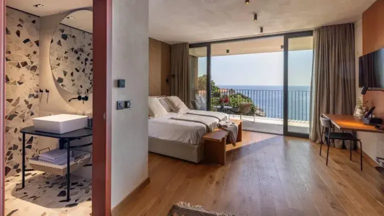 Chambre à coucher avec un lit king-size et un balcon donnant sur la mer à Villa Eleven