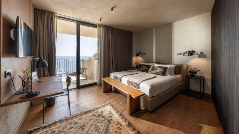 Schlafzimmer mit Kingsize-Bett, Holzbank und Meerblick in der Villa Eleven