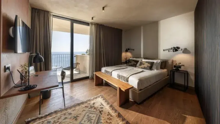 Chambre à coucher avec un lit king-size, un banc en bois et vue sur la mer à Villa Eleven