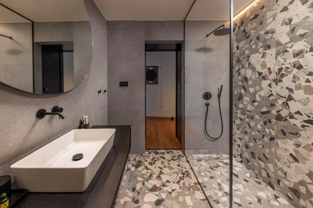 Salle de bains moderne avec douche à l’italienne, sol en terrazzo et vasque en pierre à Villa Eleven