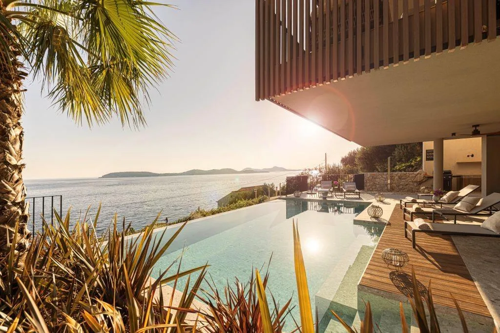 Piscine à débordement Villa Eleven au coucher du soleil avec des palmiers donnant sur la mer Adriatique à Zaton