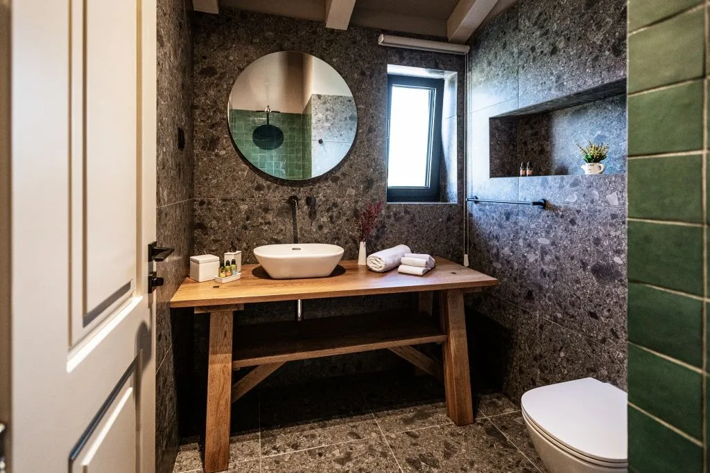 Bathroom with terrazzo walls, round mirror and wooden vanity at Villa Sol