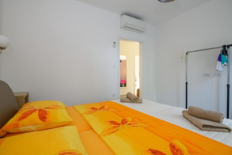 Schlafzimmer mit Queensize-Bett und orangefarbenen Bettwäsche in der Villa K