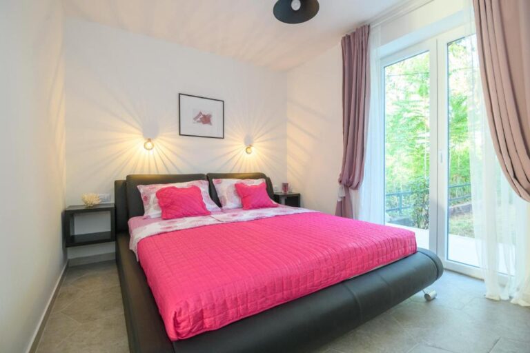 Schlafzimmer mit Queensize-Bett und rosa Bettwäsche in der Villa K
