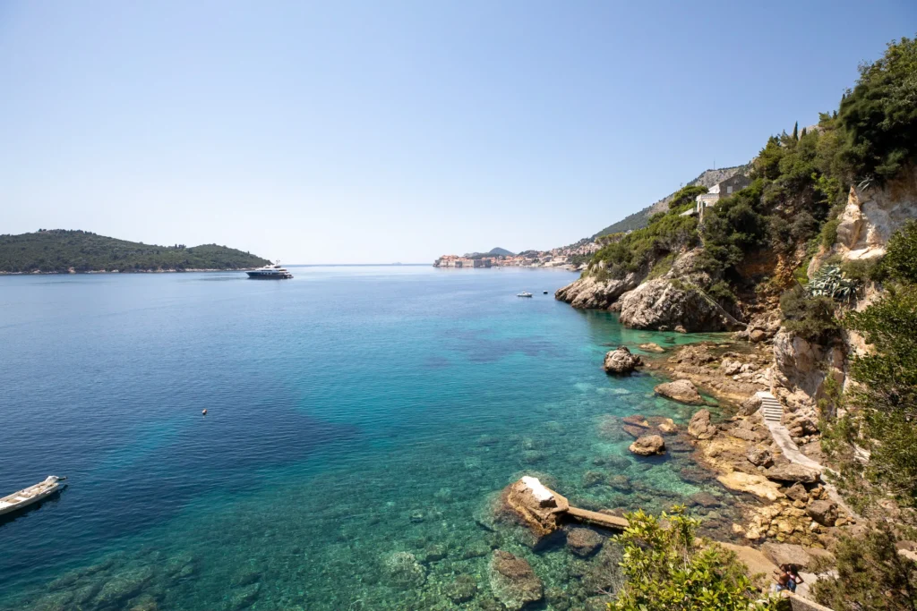 Turquoise Adriatic cove near Dubrovnik with a rocky shore, Lokrum island and the Old Town in the distance