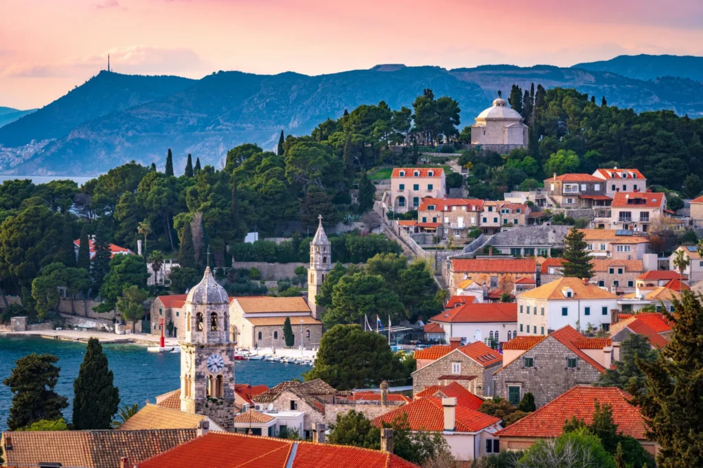 Cavtat at sunset with the clock tower, St Nicholas bell tower, harbour and the Račić Mausoleum, Dubrovnik in the distance