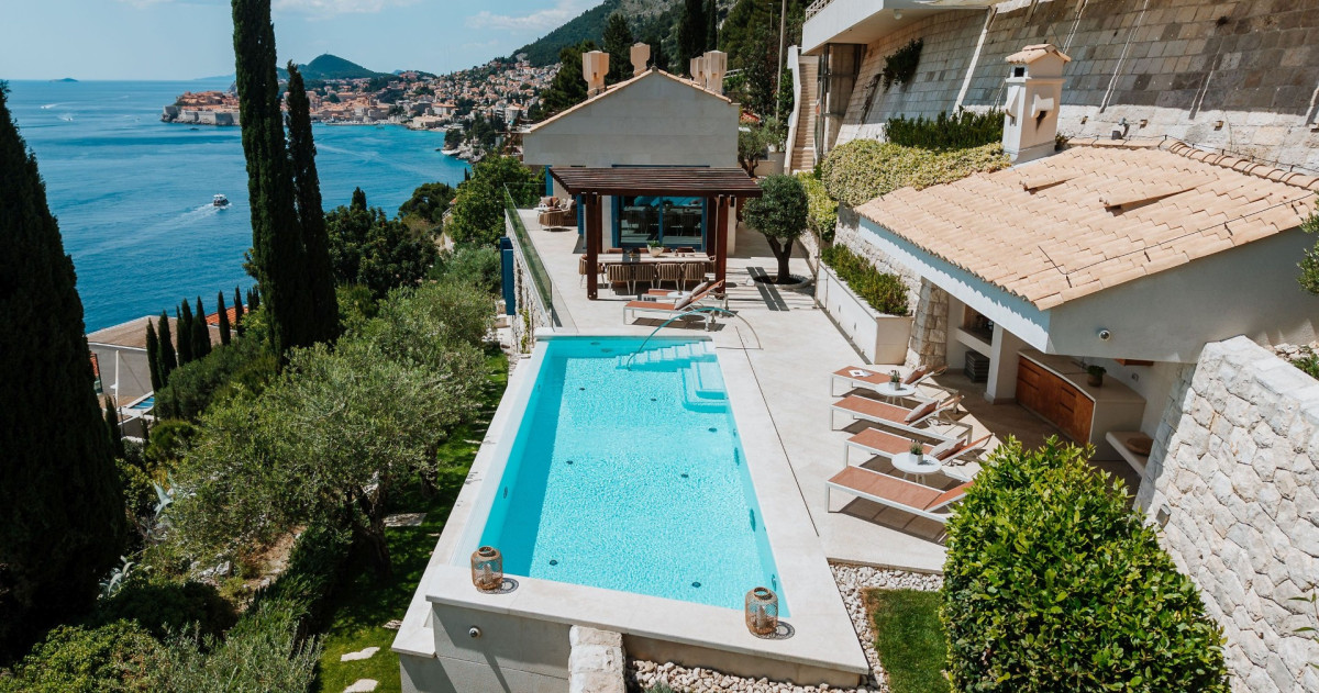 Luftaufnahme des langen privaten Pools der Villa Blazia, der Sonnenliegen und des Gartententhauses mit Olivenbäumen in Dubrovnik