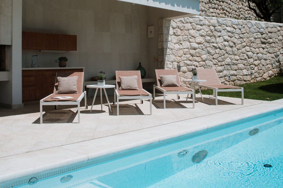 Ein überdachter Poolbereich mit Liegestühlen und eine Außerküche direkt neben dem Swimmingpool in der Villa Blazia