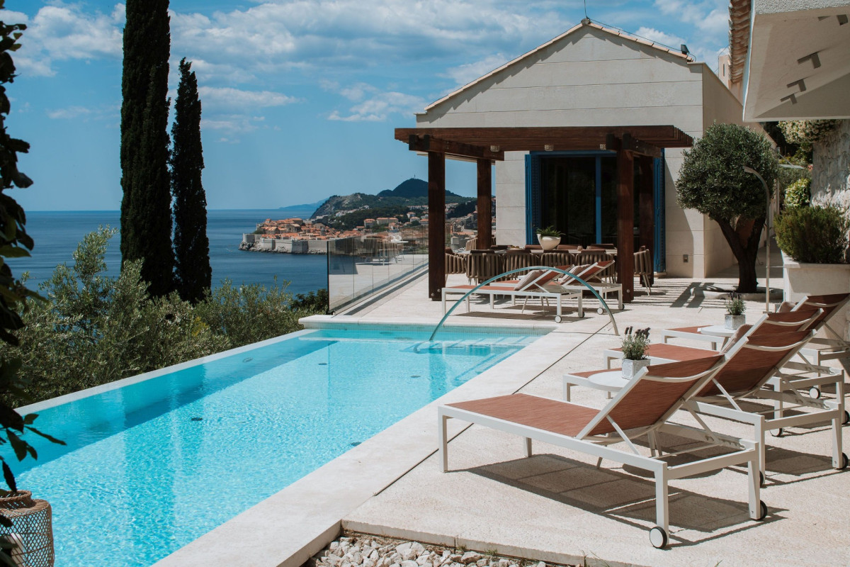 Schwimmbad mit Liegestühlen und einem Gartenpavillon in der Villa Blazia, mit dem Meer und einer Insel im Hintergrund