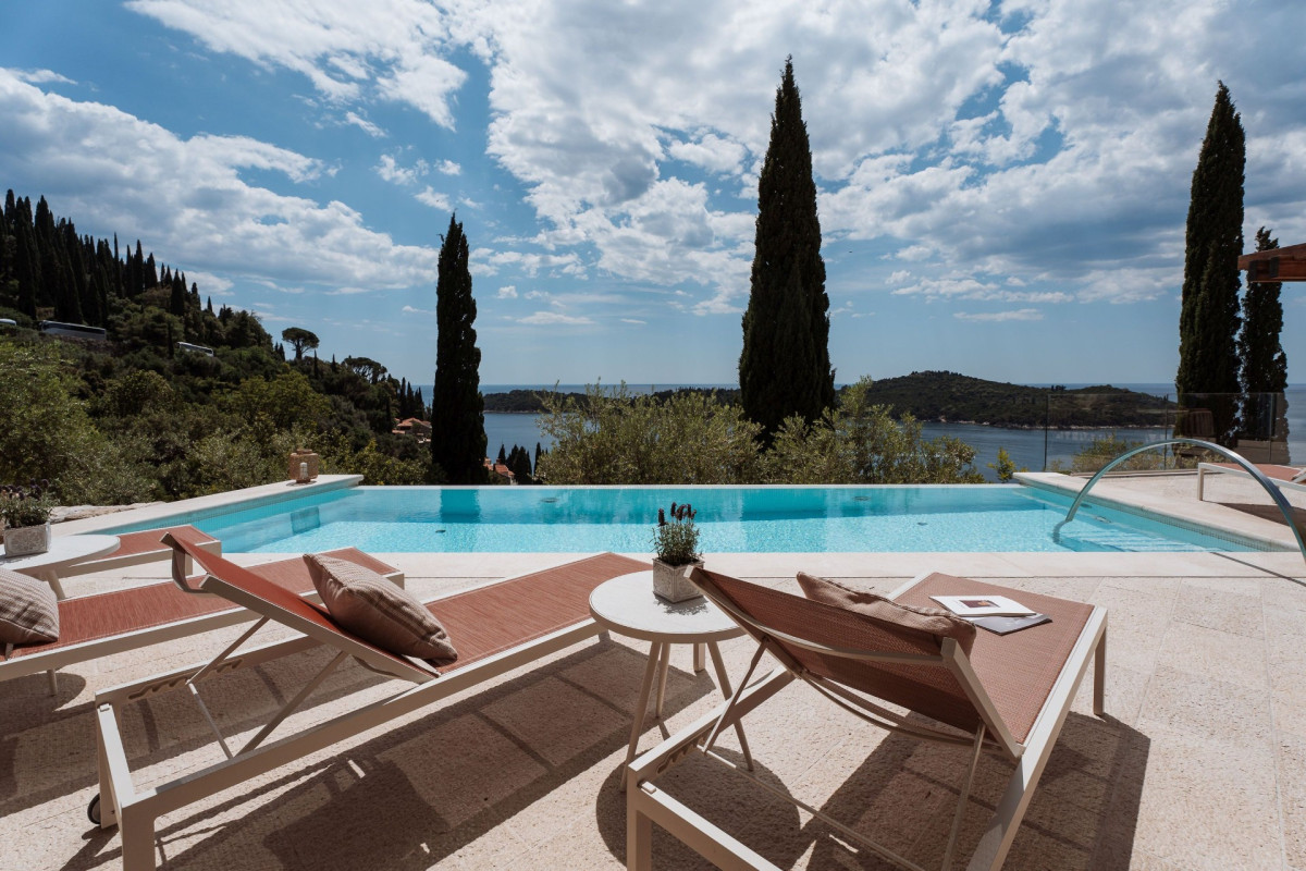 Sonnenliegen am Infinity-Pool in der Villa Blazia mit Zypressen und dem Adriatischen Meer im Hintergrund