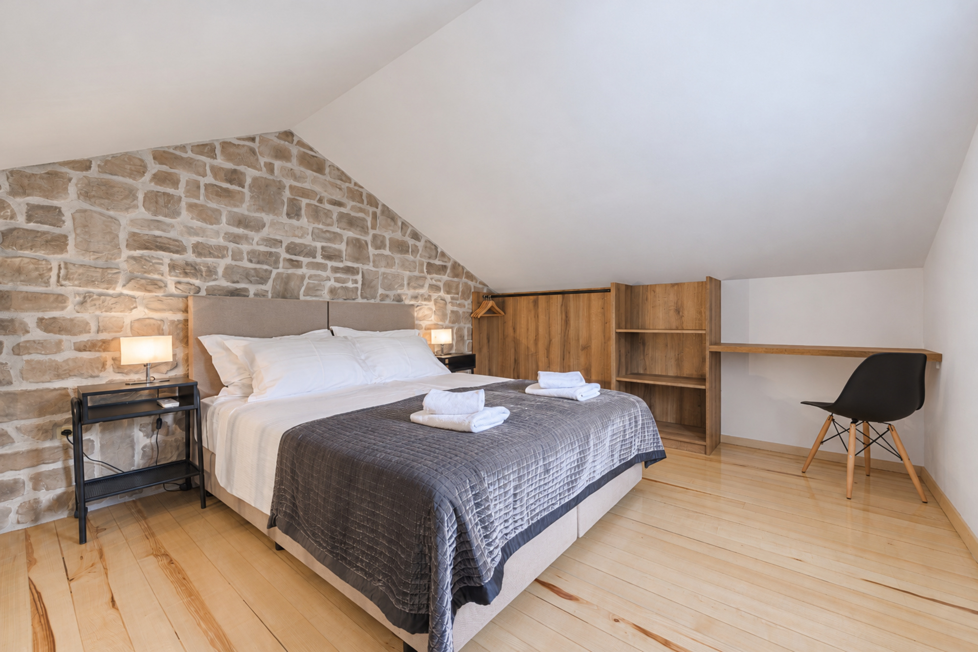Attic-Schlafzimmer mit Kingsize-Bett, freiliegender Steinwand, Kleiderschrank und Schreibtisch im Noah House in Zaton bei Dubrovnik