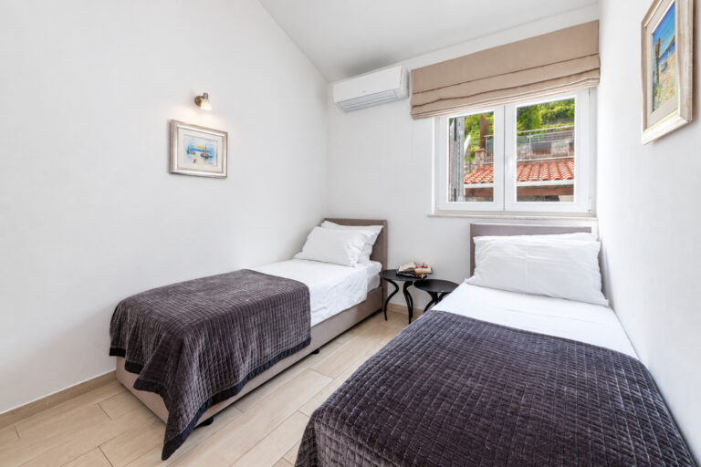 Zweibettzimmer mit zwei Einzelbetten, Klimaanlage und Fenster mit Gartenblick im Noah House in Zaton bei Dubrovnik